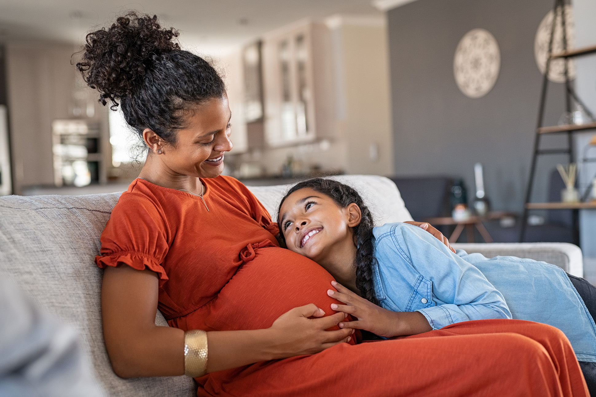 Happy lovely daughter hugging pregnant mother