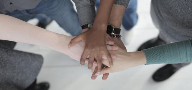 Crop unrecognizable multiethnic colleagues joining hands