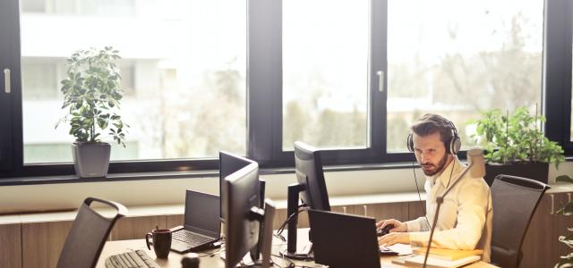 Man with headphones facing computer monitor